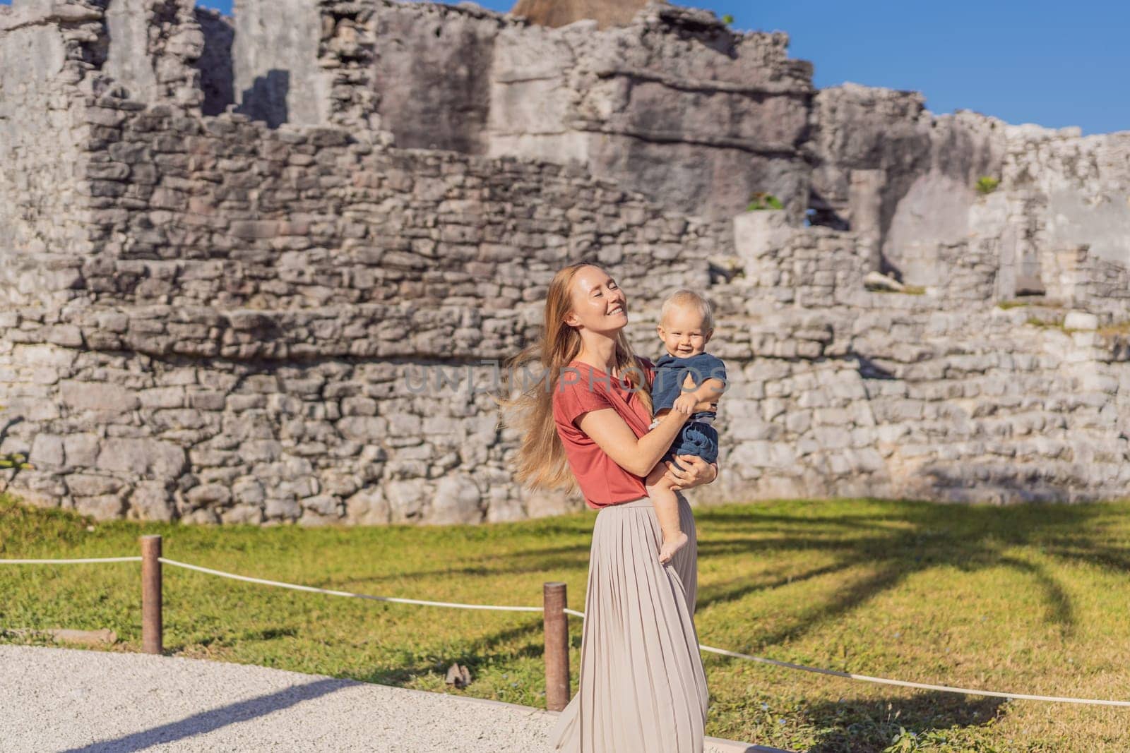 Mother and son tourists enjoying the view Pre-Columbian Mayan walled city of Tulum, Quintana Roo, Mexico, North America, Tulum, Mexico. El Castillo - castle the Mayan city of Tulum main temple.