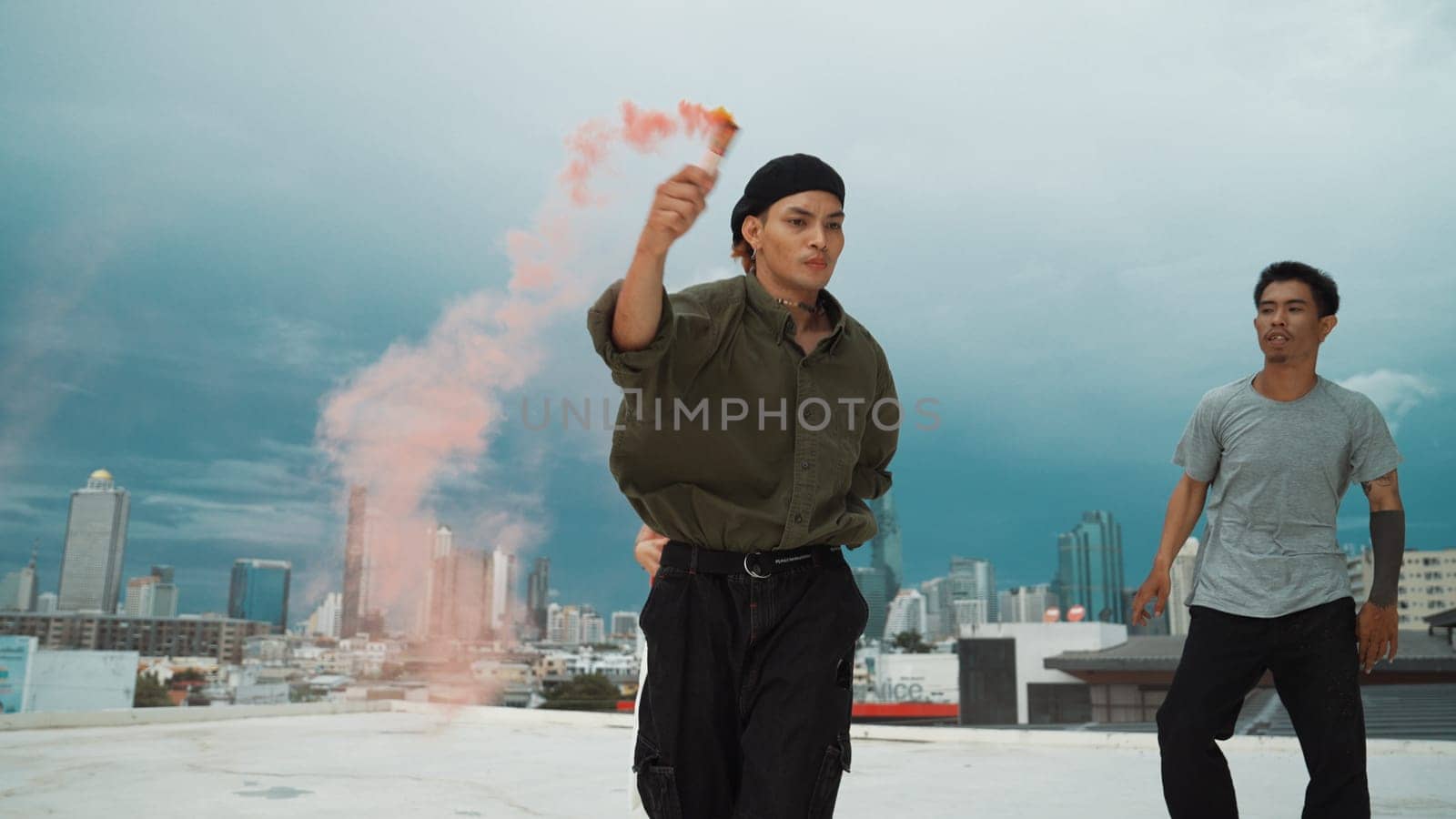 Group of multicultural hipster playing color flare at rooftop. Attractive street dancer holding colored smoke and perform break dance move to hip-hop music. Outdoor sport 2024. Endeavor.