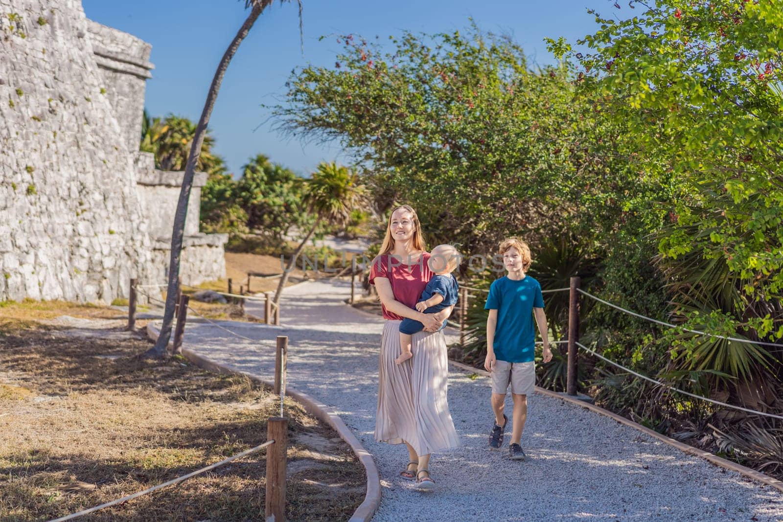 Mother and two sons tourists enjoying the view Pre-Columbian Mayan walled city of Tulum, Quintana Roo, Mexico, North America, Tulum, Mexico. El Castillo - castle the Mayan city of Tulum main temple.