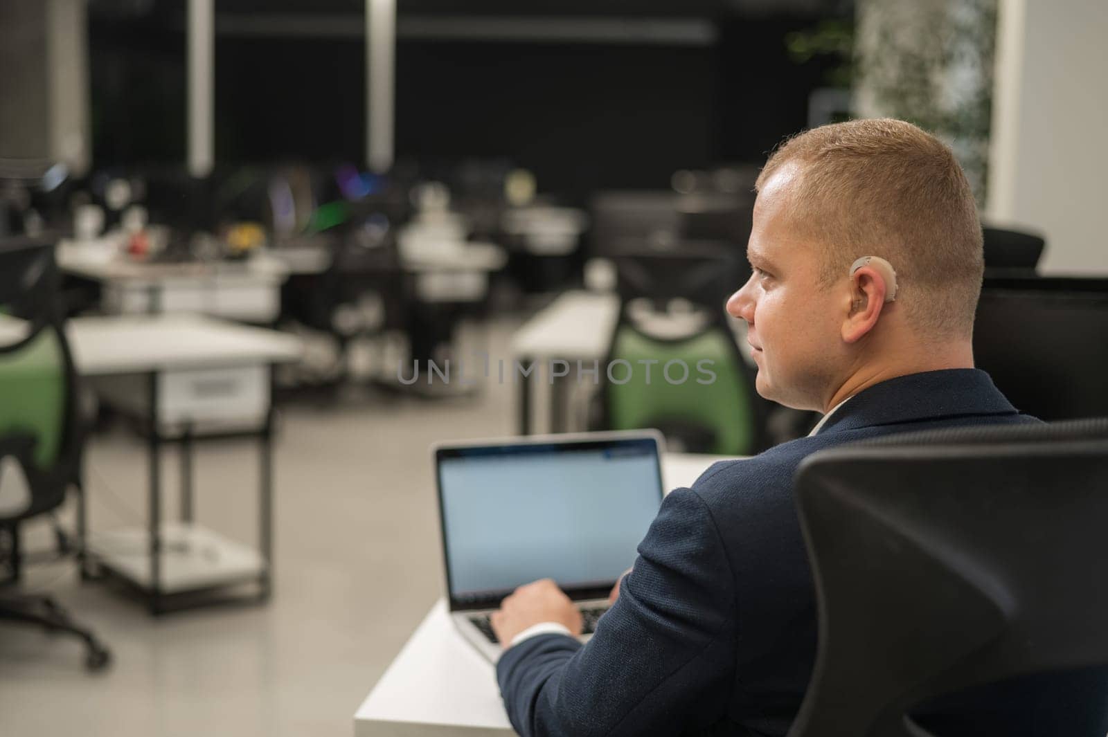 Caucasian deaf man typing on laptop in office
