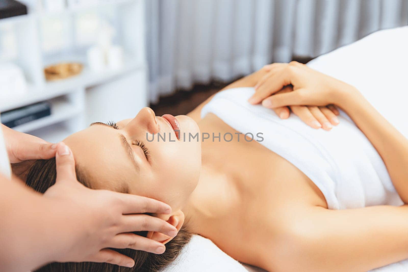 Caucasian woman enjoying relaxing anti-stress head massage and pampering facial beauty skin recreation leisure in dayspa modern light ambient at luxury resort or hotel spa salon. Quiescent