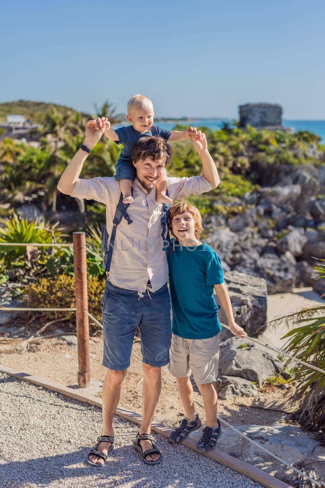 Father and two sons tourists enjoying the view Pre-Columbian Mayan walled city of Tulum, Quintana Roo, Mexico, North America, Tulum, Mexico. El Castillo - castle the Mayan city of Tulum main temple.