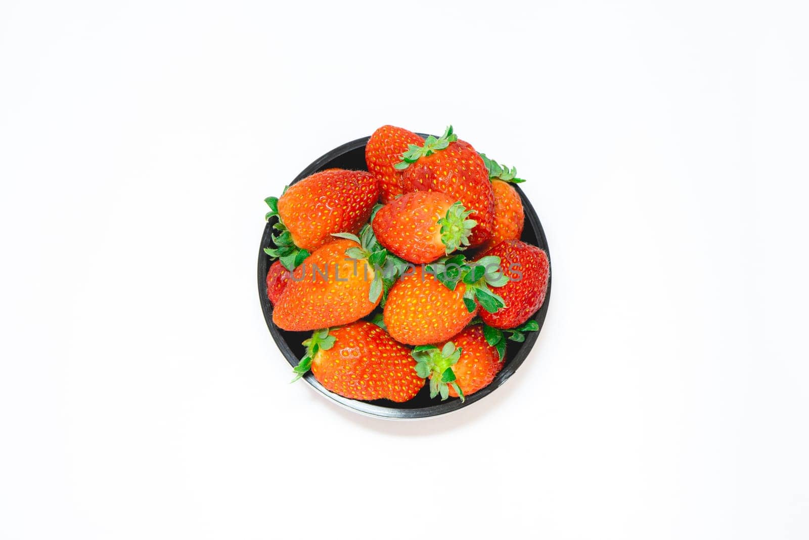 black bowl with fresh strawberries on a white background.