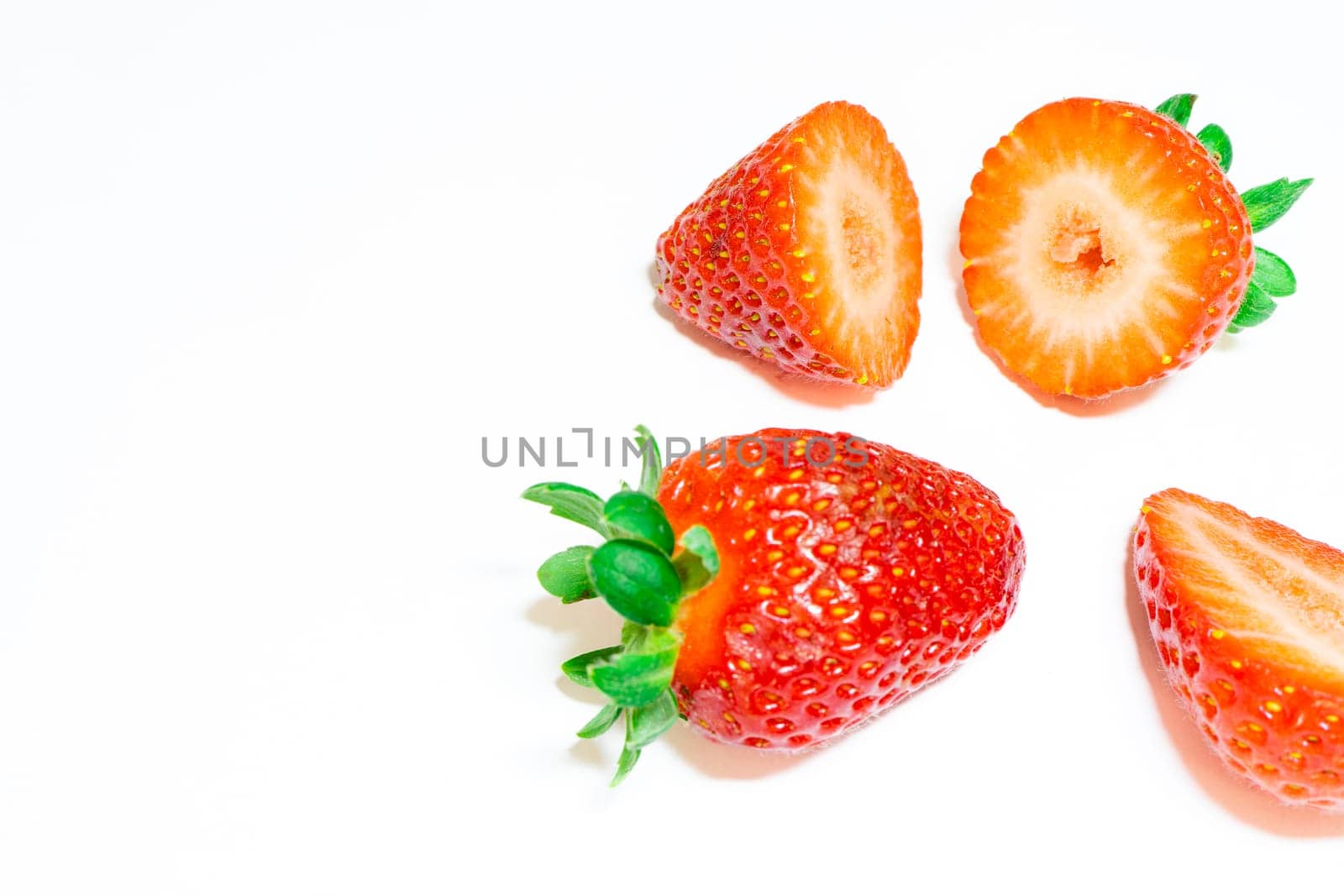 Peaces of fresh strawberries on a white background.