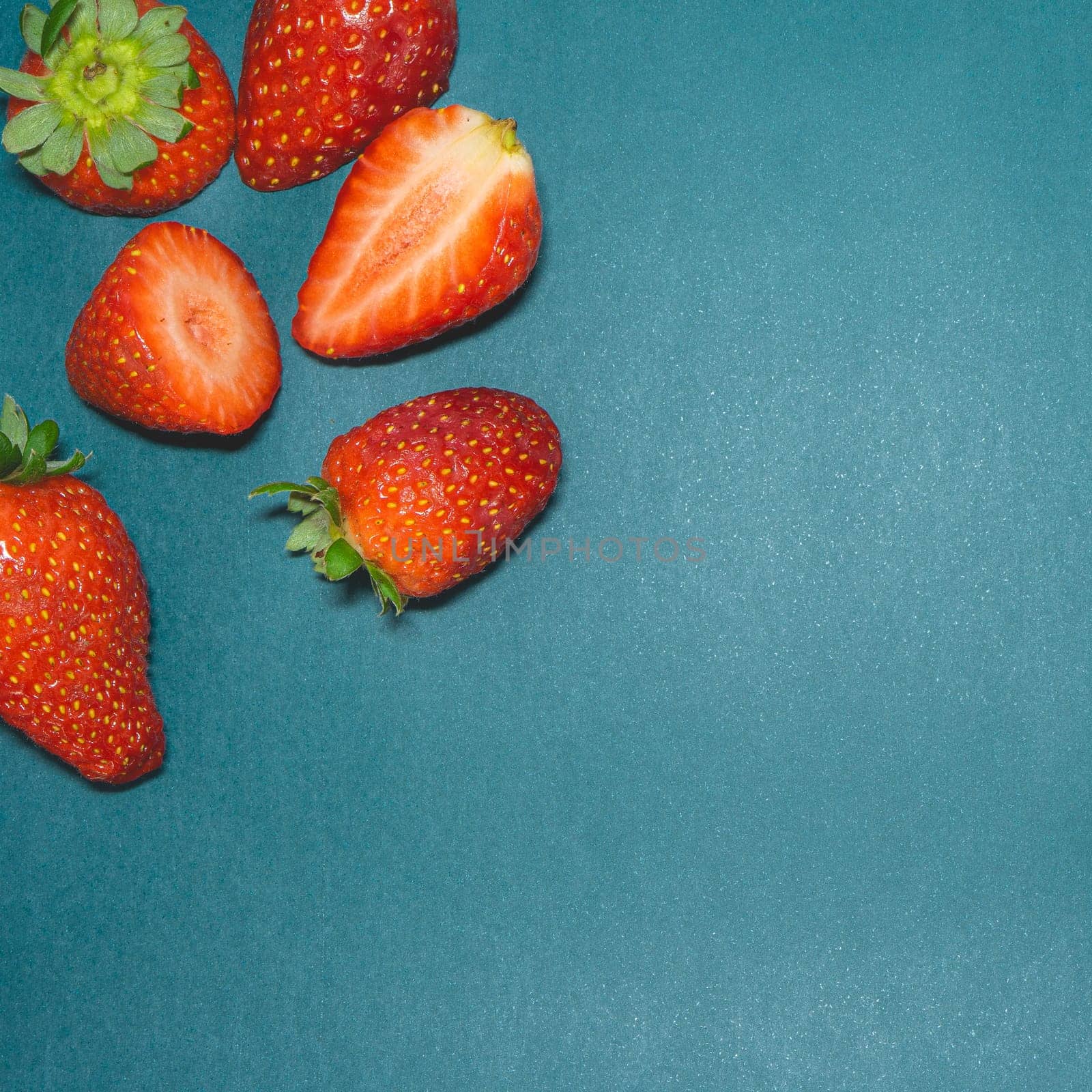 Peaces of fresh strawberries on a blue background.