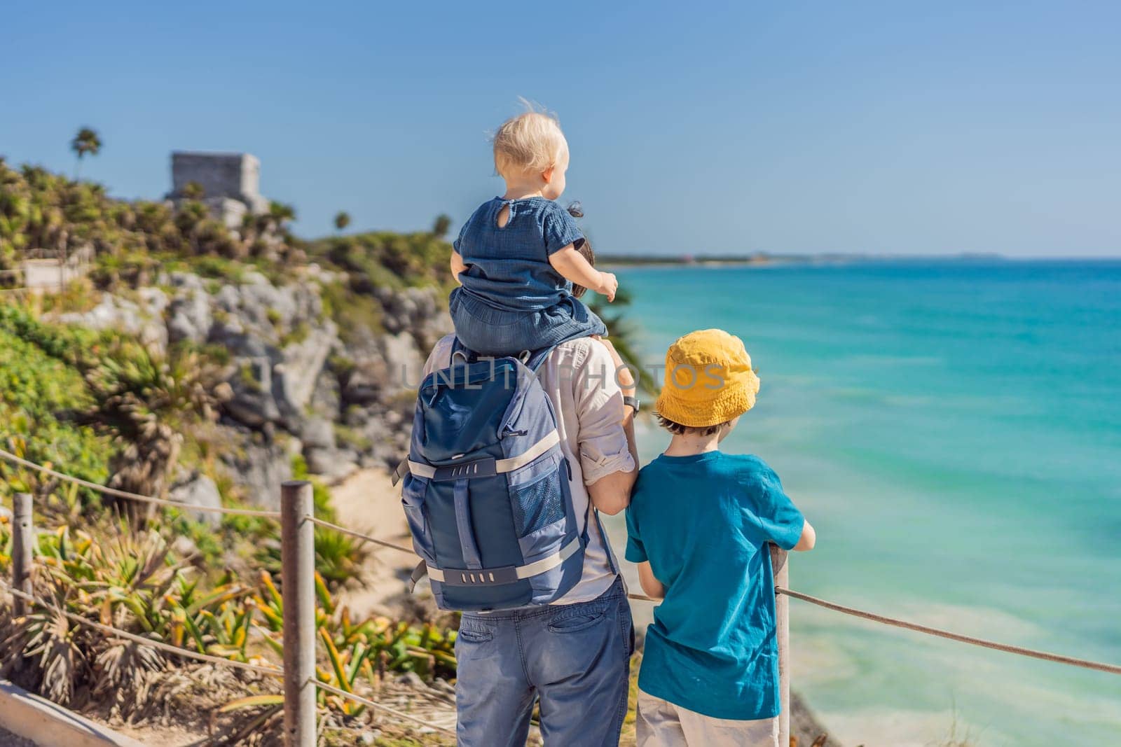 Father and two sons tourists enjoying the view Pre-Columbian Mayan walled city of Tulum, Quintana Roo, Mexico, North America, Tulum, Mexico. El Castillo - castle the Mayan city of Tulum main temple.