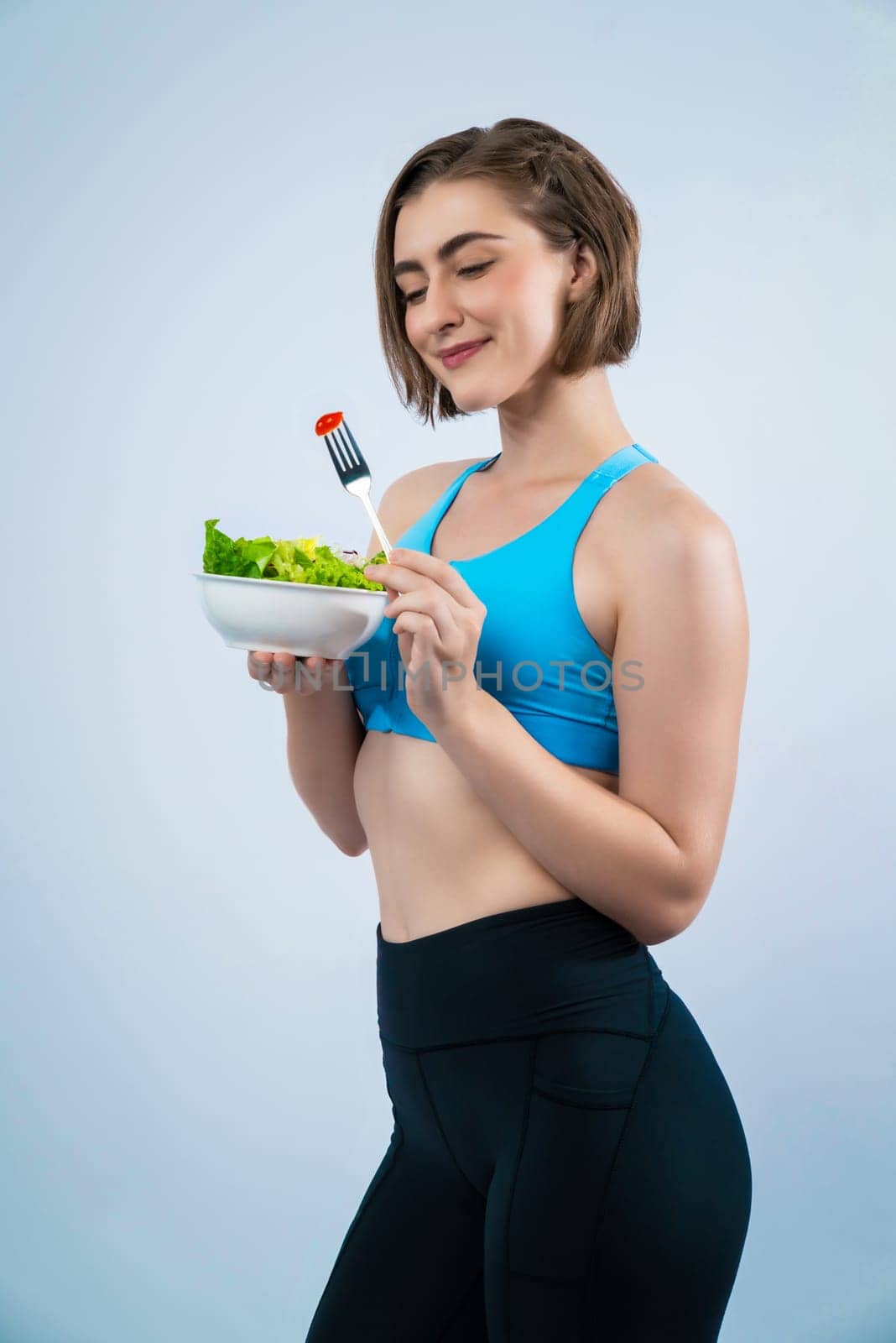 Full body length gaiety shot athletic and sporty young woman with healthy vegan food in standing posture on isolated background. Healthy active and body care by vegetarian lifestyle.