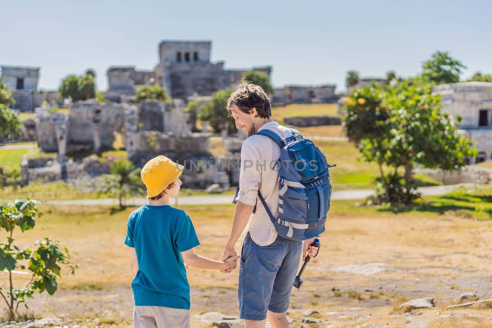 Father and son tourists enjoying the view Pre-Columbian Mayan walled city of Tulum, Quintana Roo, Mexico, North America, Tulum, Mexico. El Castillo - castle the Mayan city of Tulum main temple.