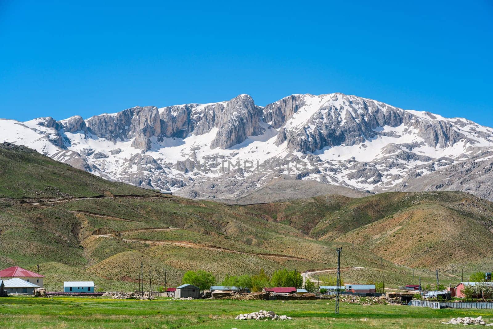 The lush green Sobucimen plateau in spring and the mountains with some melted snow behind.