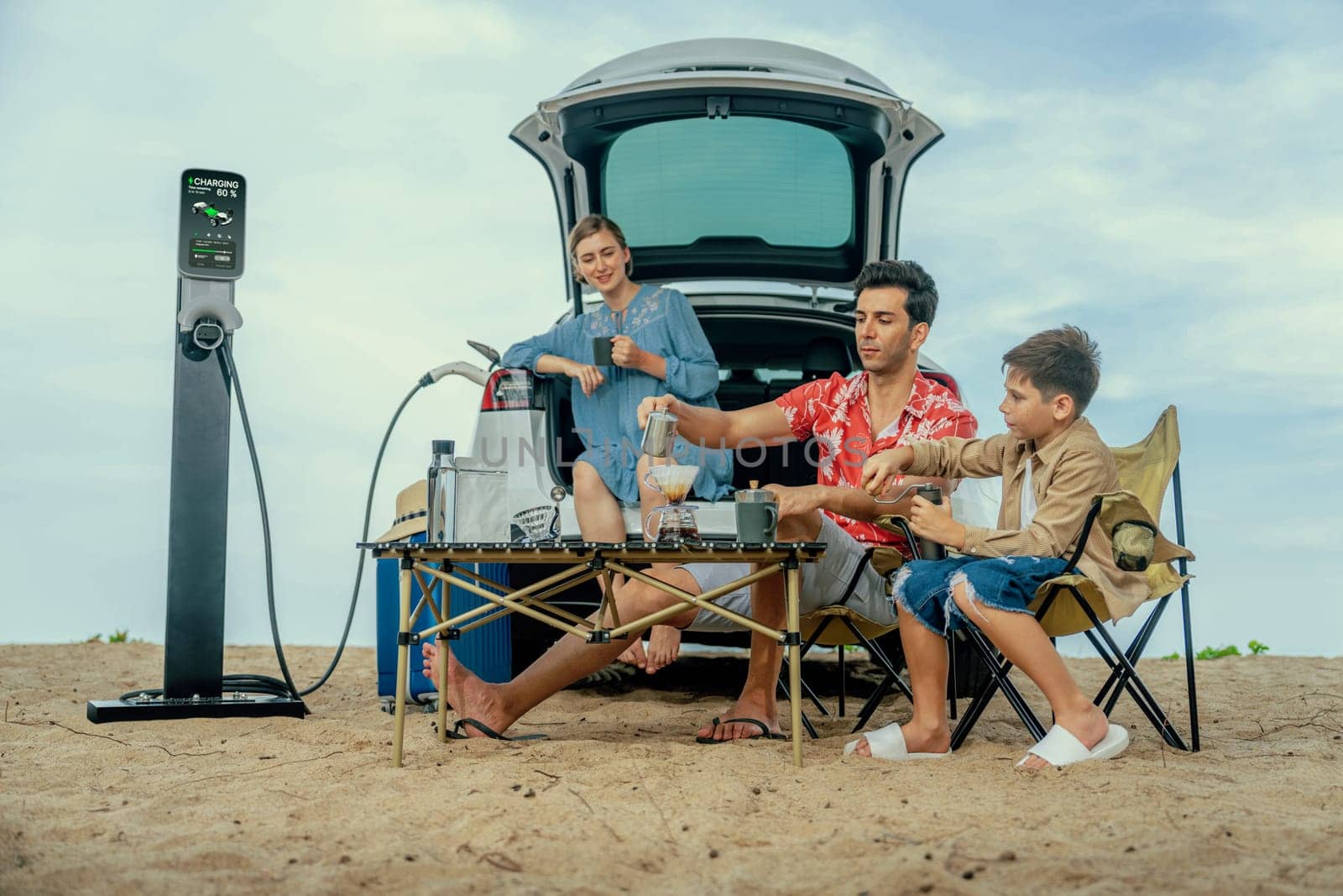 Family vacation trip traveling by the beach with electric car, happy family recharge EV car, enjoying outdoor camping coffee. Seascape travel and eco-friendly car for clean environment. Perpetual