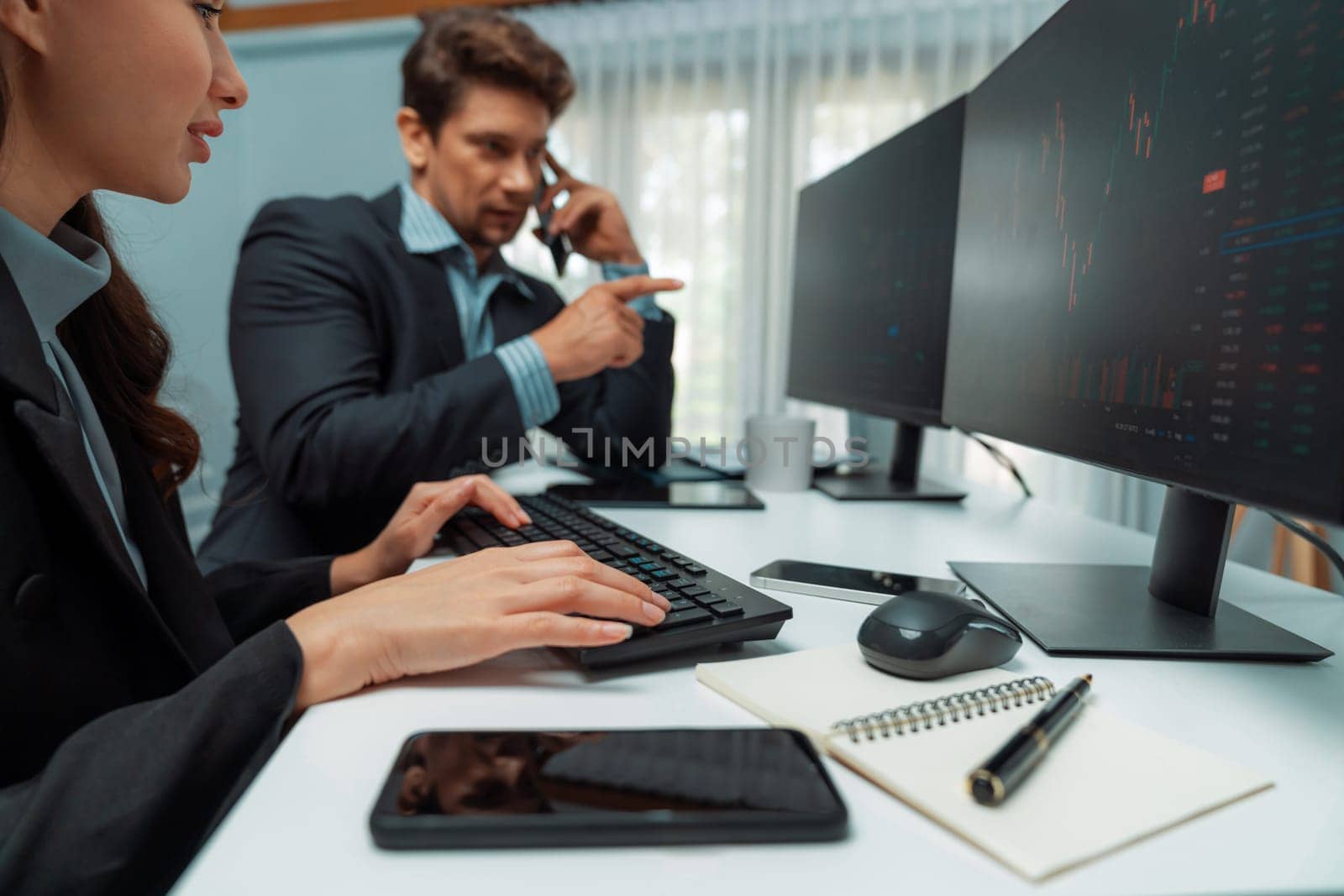 A man broker calling trader businessman to inform high profit point of stock exchange in digital currency while a woman assistance pointing to analyzed data monitor on real time at office. Postulate.