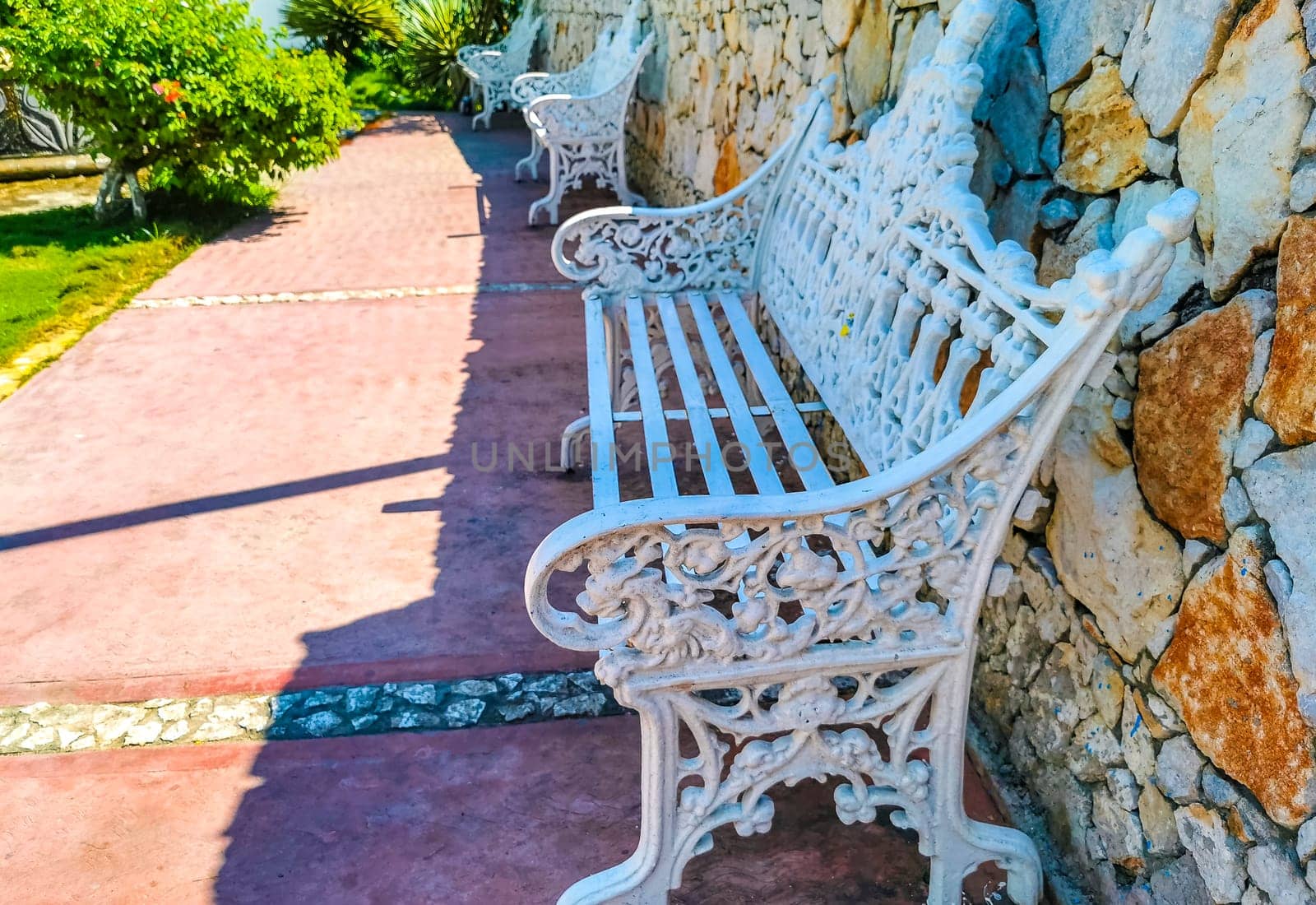White metal park bench at the roadside Puerto Escondido Mexico. by Arkadij