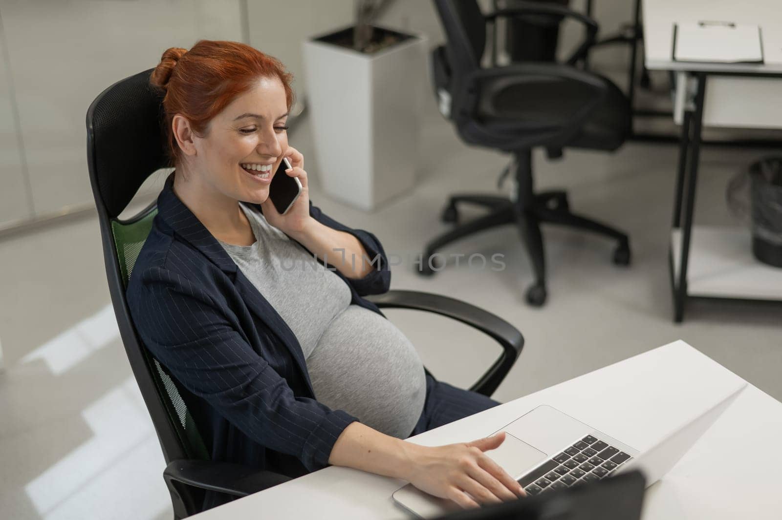 Pregnant woman using mobile phone in office