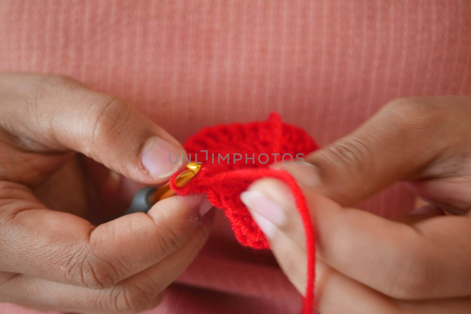 Hand close up crocheting with a hook, wool yarn, creative craft.