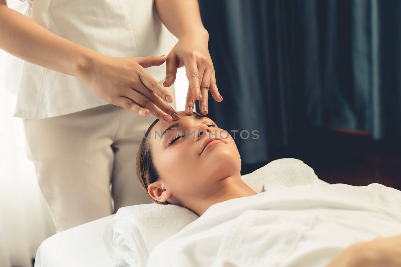 Caucasian woman enjoying relaxing anti-stress head massage and pampering facial beauty skin recreation leisure in dayspa modern light ambient at luxury resort or hotel spa salon. Quiescent