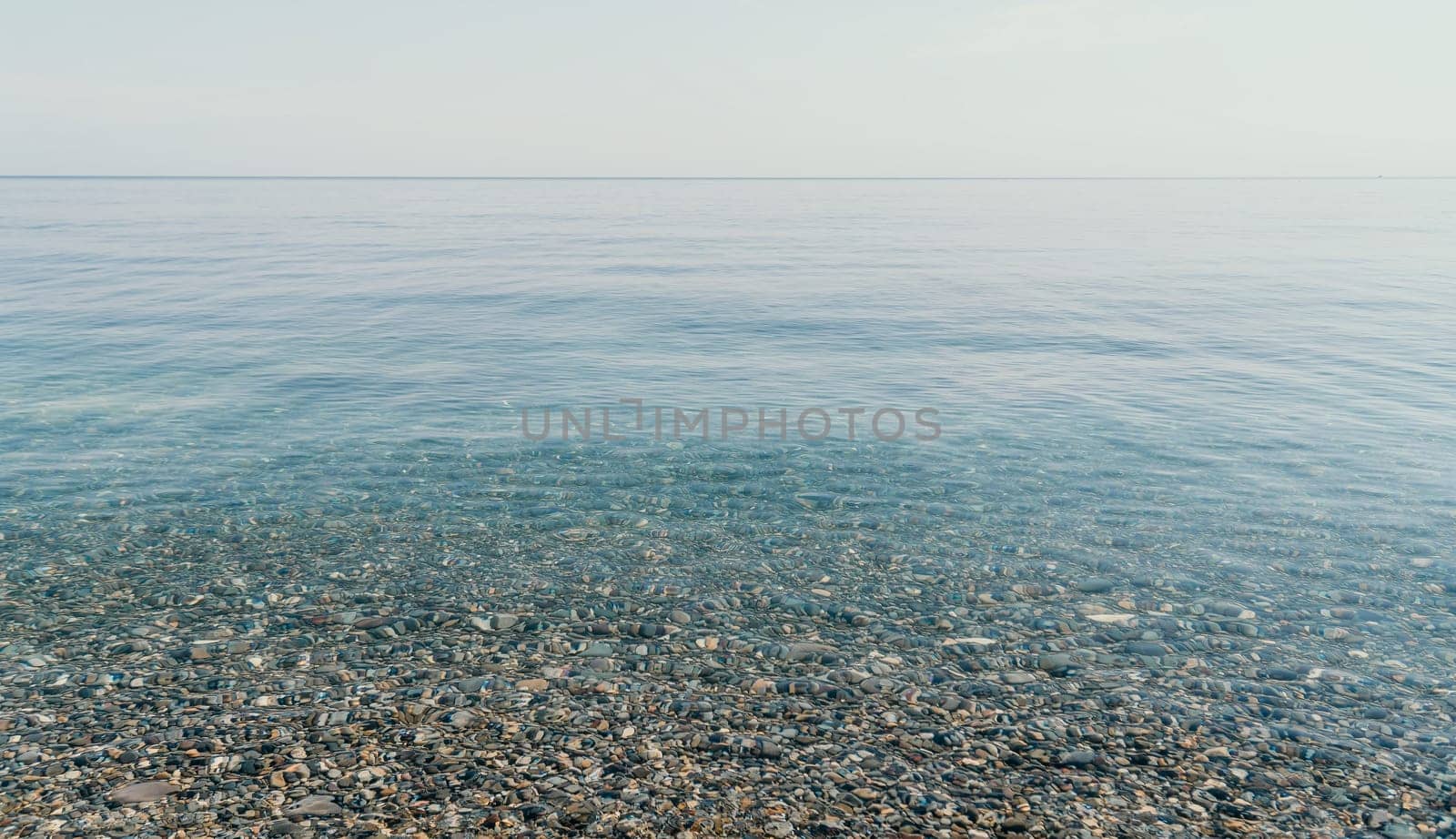 A calm body of water with a few rocks scattered throughout. The water appears to be clear and still, with no visible waves or ripples. The rocks are of various sizes