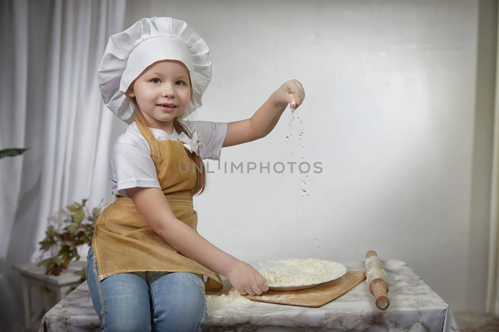 Cute oriental girl cooking in the kitchen on Ramadan, Kurban-Bairam, Eid al-Adha. Funny female child at cook photo shoot. Pancakes, Maslenitsa, Easter
