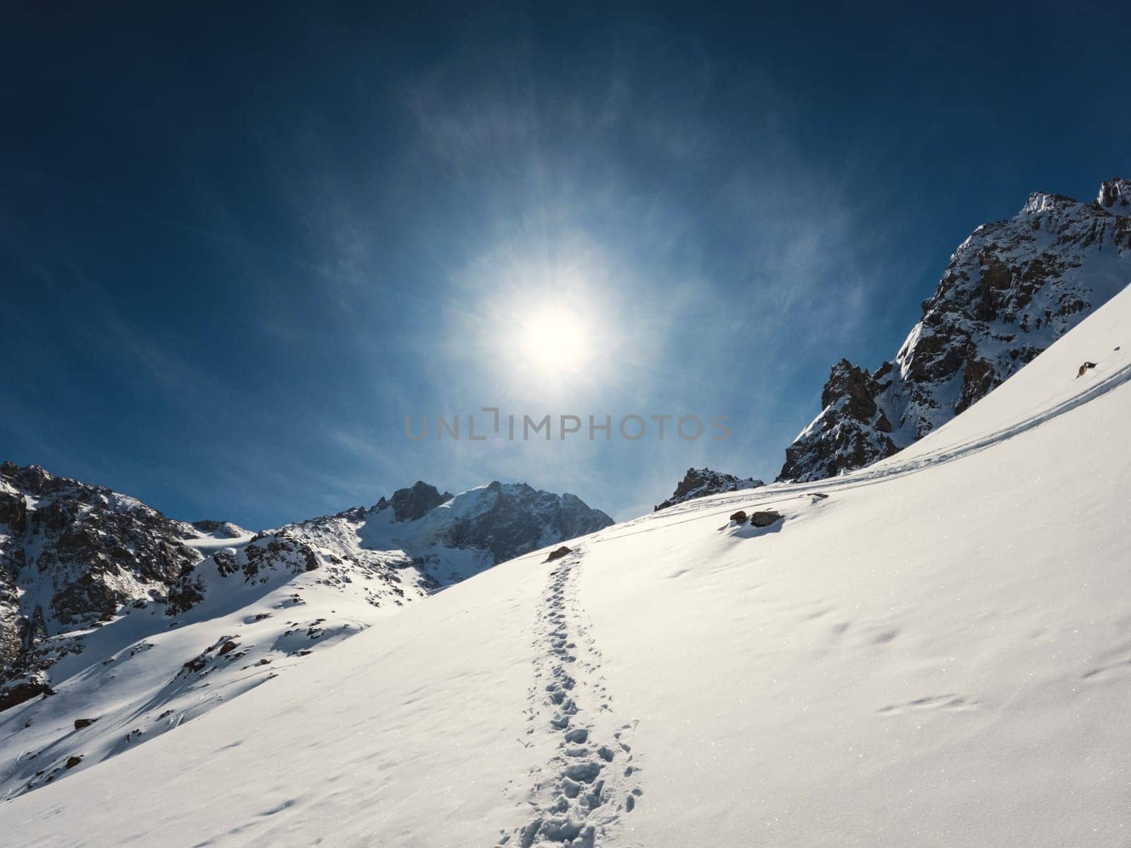 A stunning landscape of a snowcovered mountain with the sun shining through the clouds, creating a breathtaking view of the freezing slopes and icy caps.