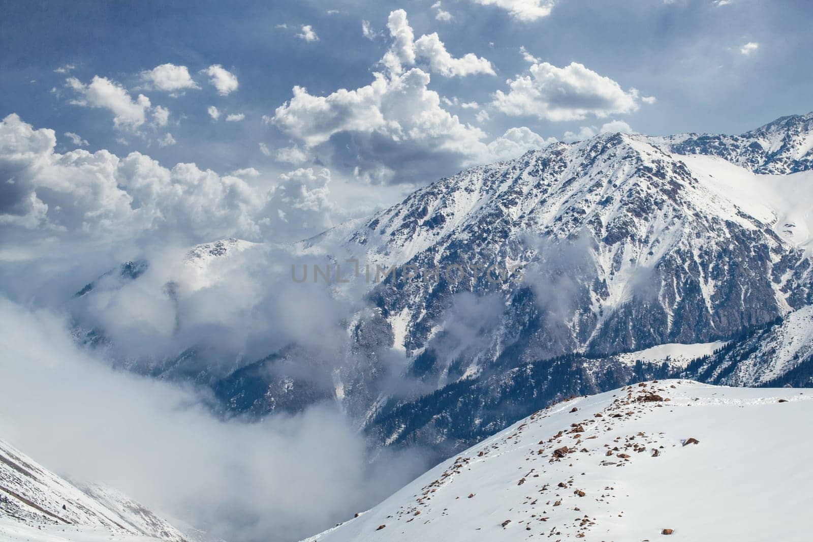 Beautiful amazing landscape of snowy mountains buried in picturesque clouds in central Asia in the Tian Shan mountains in Kazakhstan.