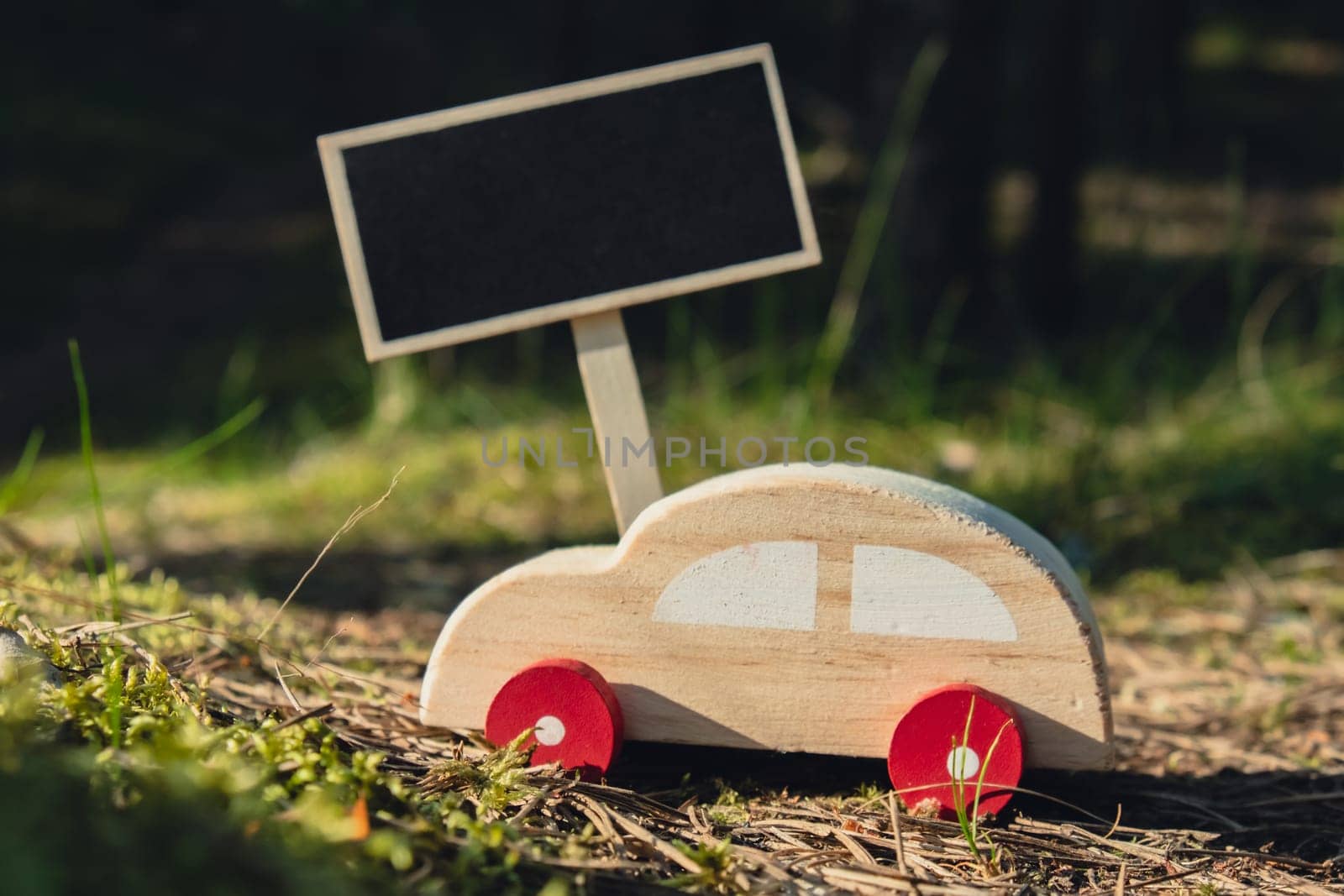 Empty blackboard with copy space Wooden toy car on greenery forest background. Eco-car concept World car free day electric vehicle environment automobile transportation electric vehicle. Hybrid electric. Sustainable engine. Zero CO2 emission for natural awareness and green environment pollution concept