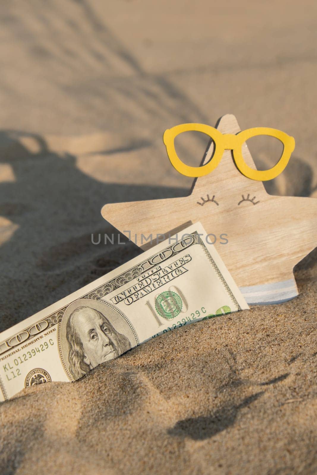 Money american hundred dollar bills in sandy beach with starfish. Concept finance saving money for holiday vacation. Costs in travel holidays. Shadows