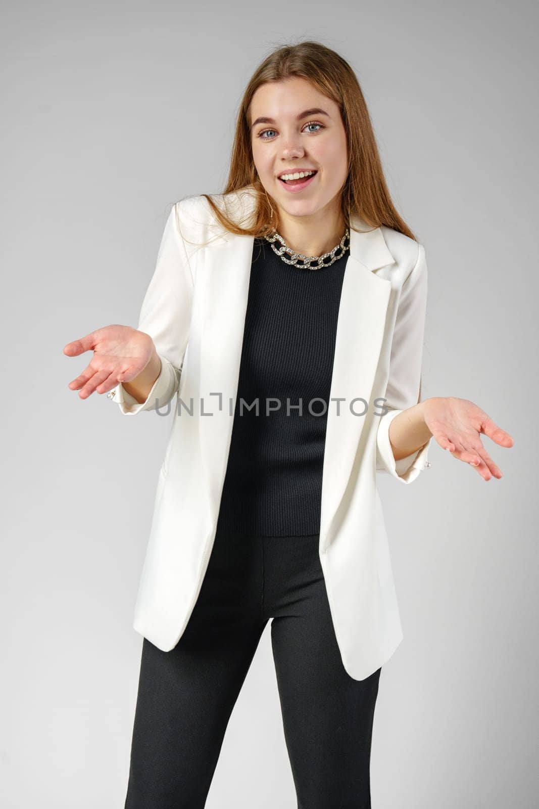 Young Woman Expressing Confusion With Hands Raised Against a Grey Background in studio