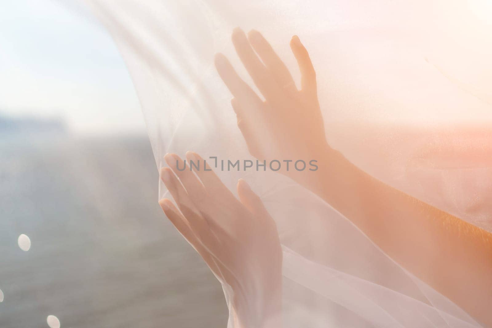 A woman stands on a beach with a white veil over her head. The scene is serene and peaceful, with the woman's gaze directed towards the water. by Matiunina