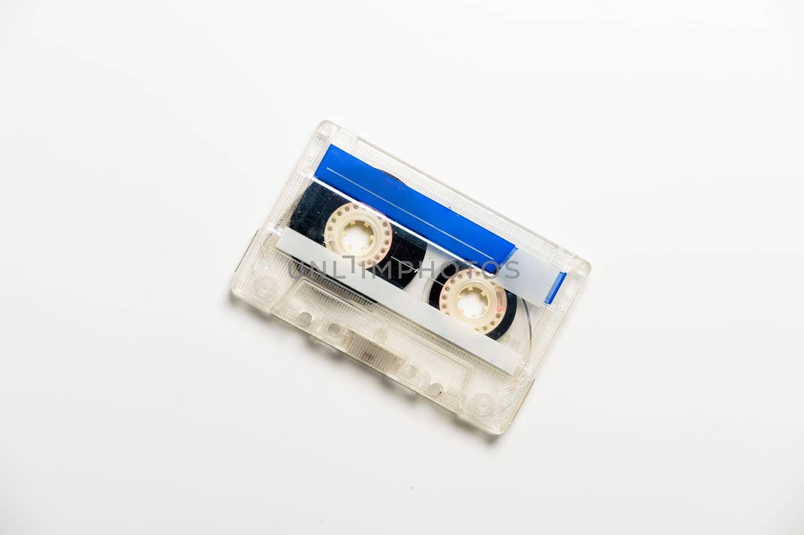 Audio cassette with black tape on a white background, top view. Template for inscription.