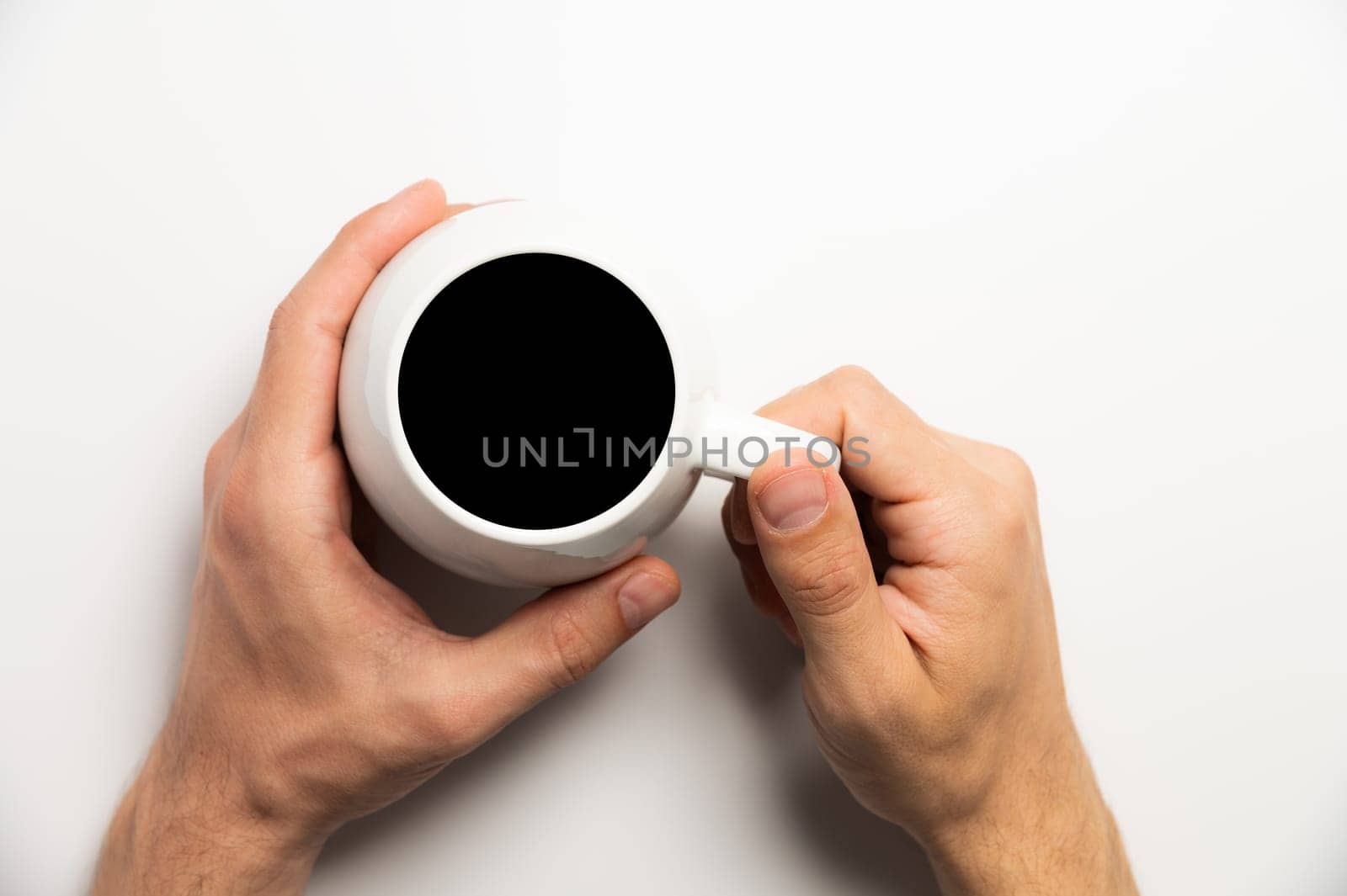 Hand holds a cup of hot chocolate cocoa drink on a white background. View from above. Flat layout. Mock-up isolated black