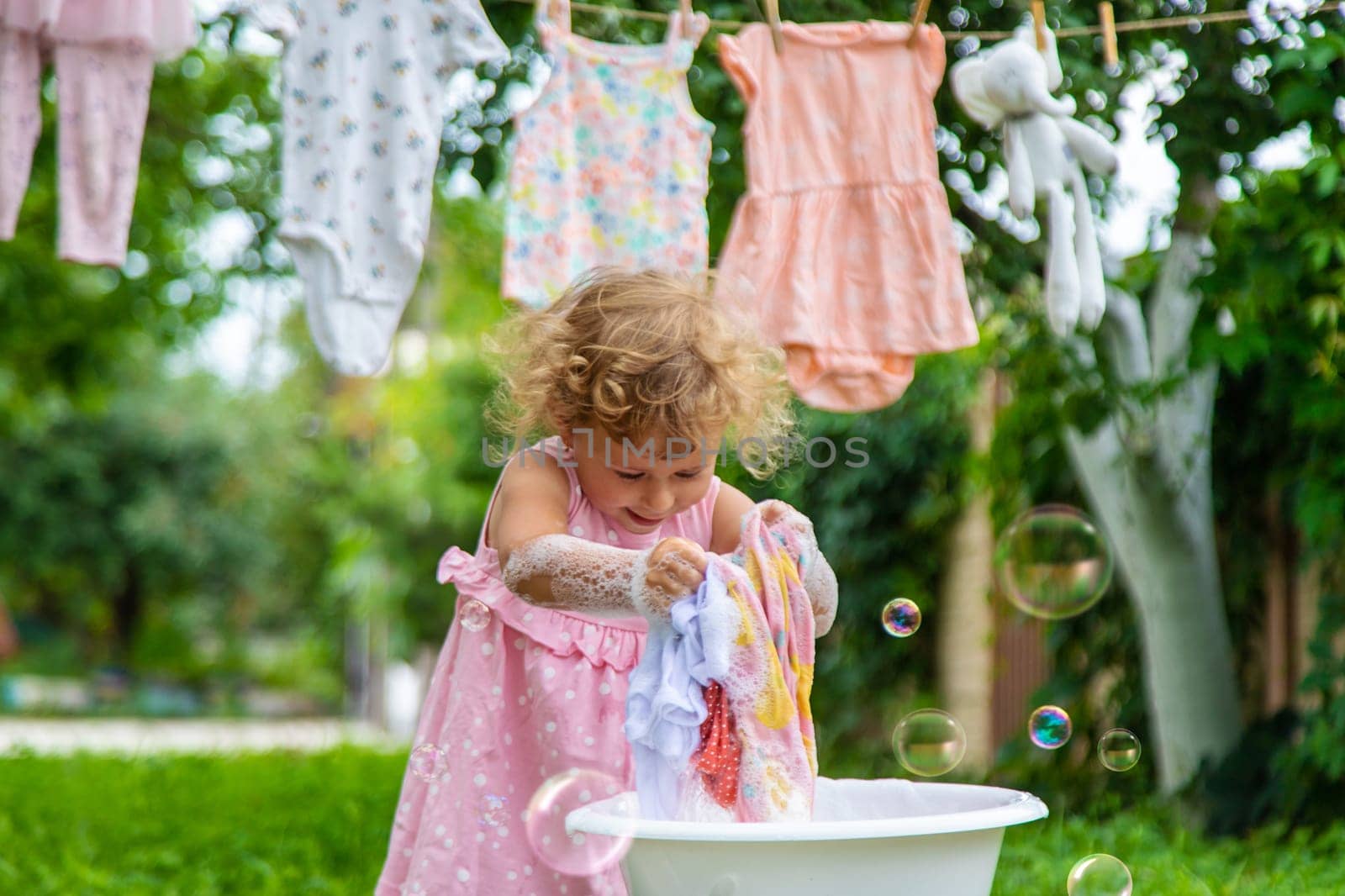 The child washes clothes and toys. Selective focus. Kid.