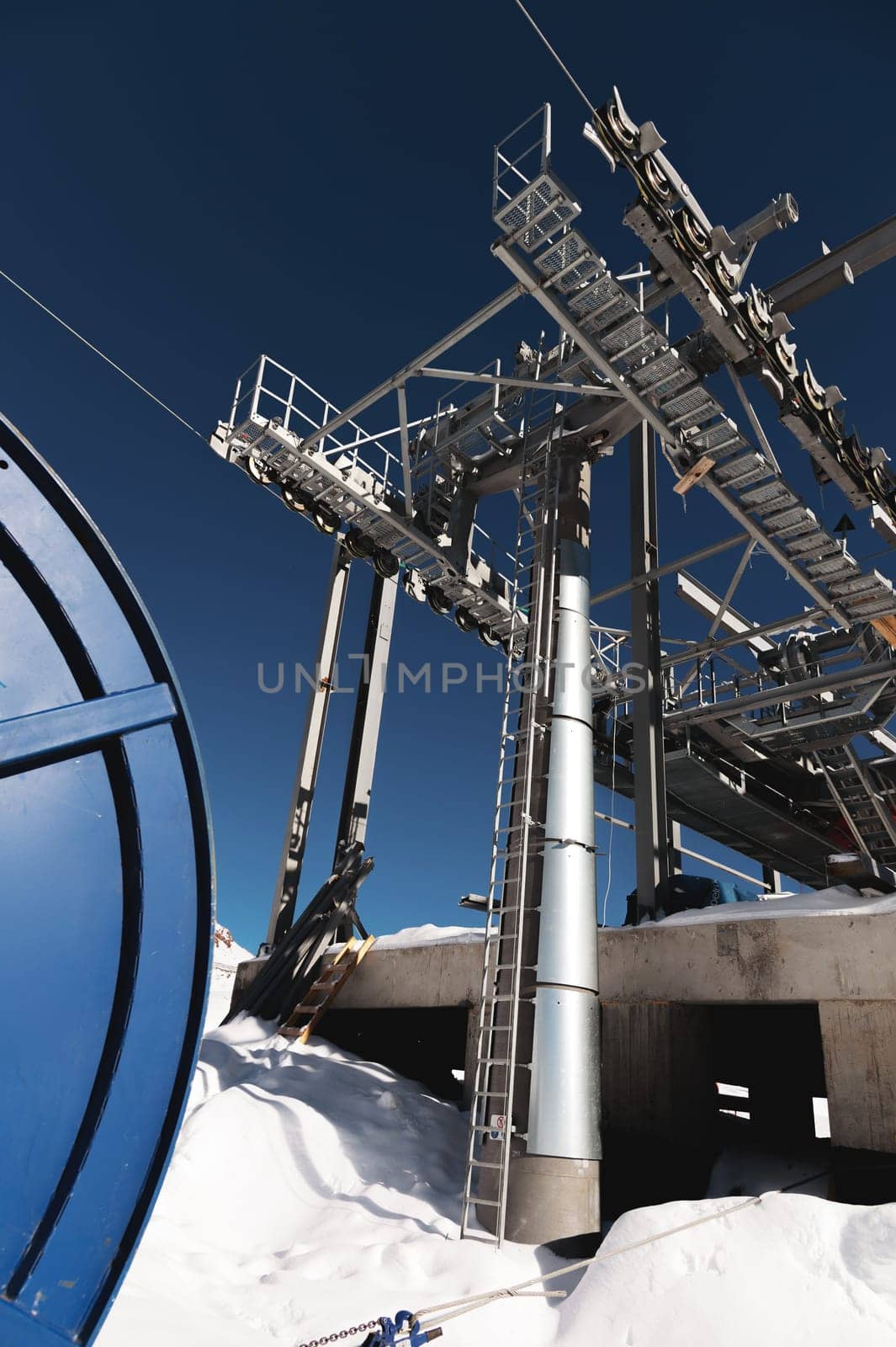 A cable car station high in the mountains under construction. Snowy mountain landscape and construction of a metal structure for a cable car.