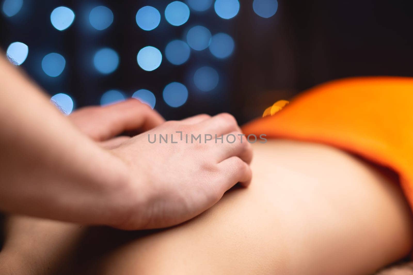 Close-up of a woman's neck and trapezium being massaged by a male masseur in shallow depth of field.