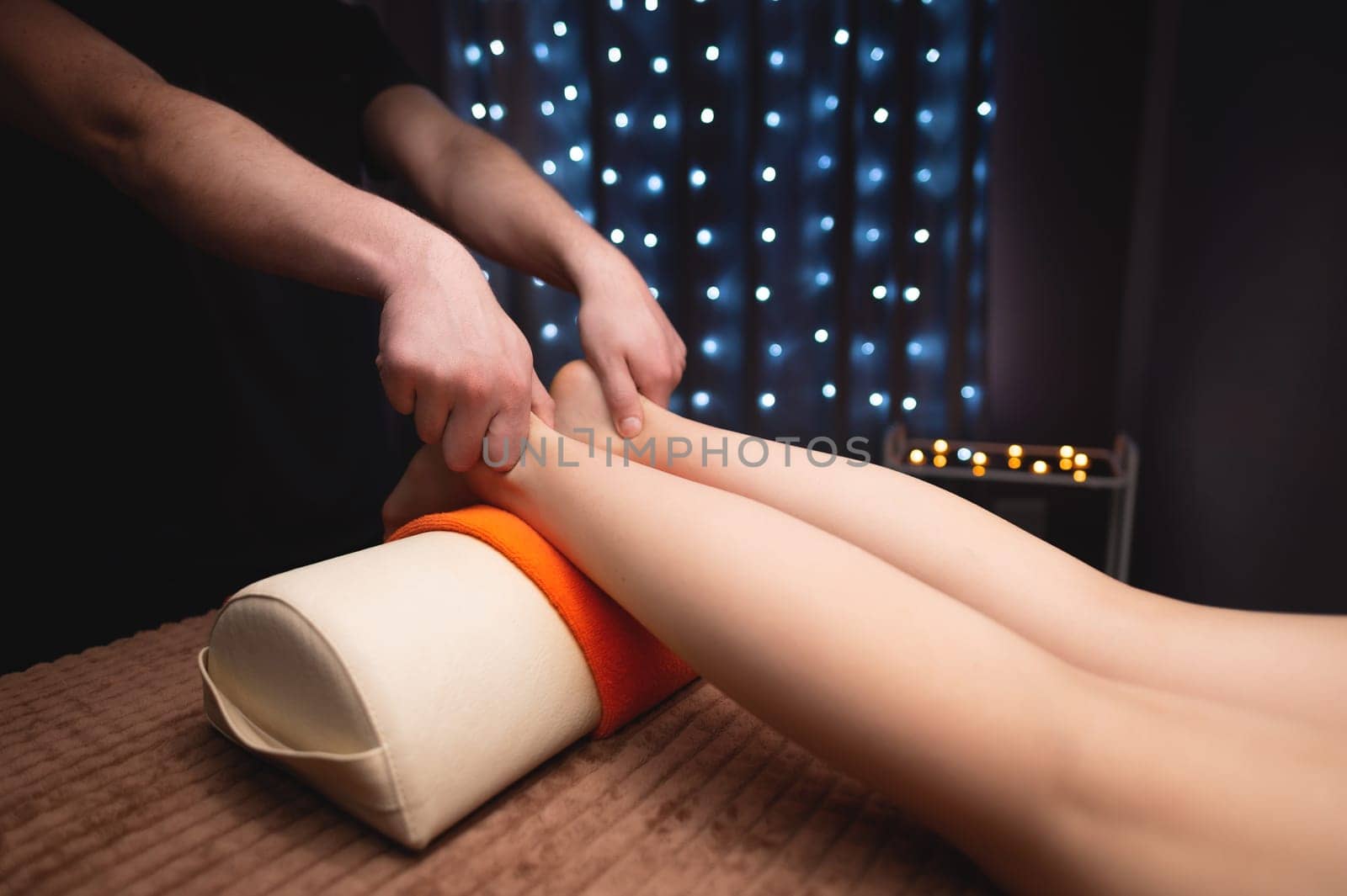 A woman is given a relaxing massage with essential oils, a man massage therapist kneads her thighs with his hands, anti-cellulite procedures.