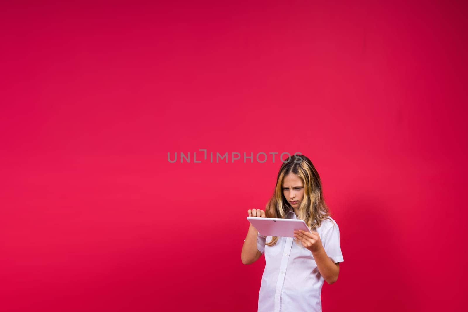 Online school app. Schoolgirl showing tablet computer Empty Screen Over red Background. Studio Shot by Zelenin