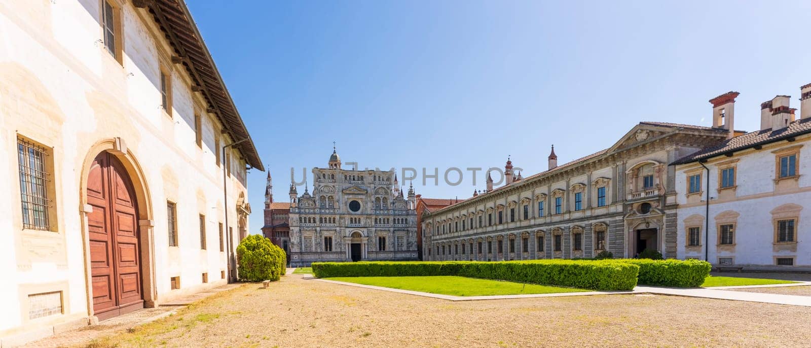 Certosa di Pavia monastery, historical monumental complex that includes a monastery and a sanctuary. green court and a church.The Ducale Palace on the right,Pavia,Italy.