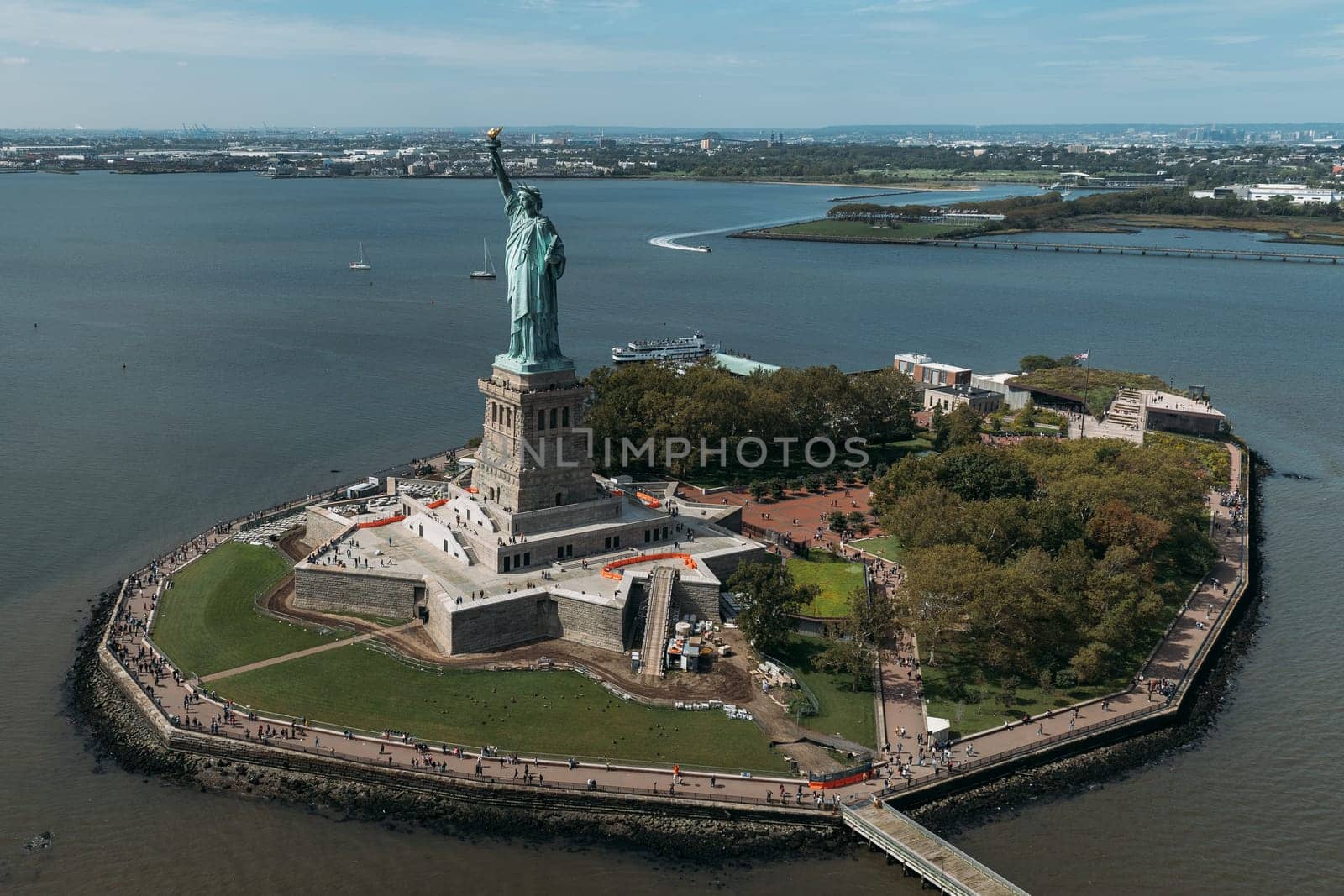 A stunning aerial view of the Statue of Liberty standing proudly on Liberty Island, surrounded by the waters of New York Harbor. The iconic monument is a symbol of freedom and democracy.