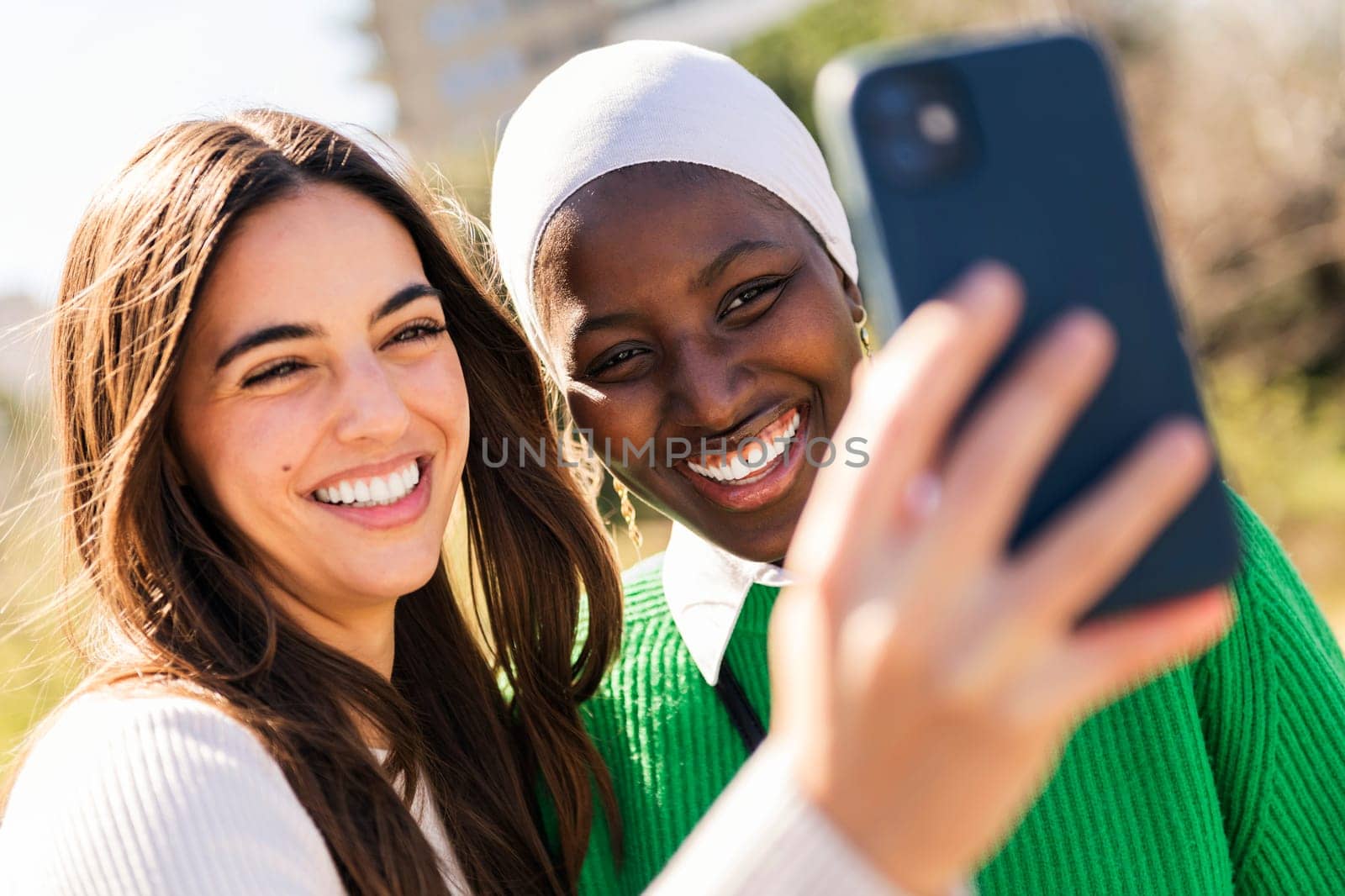two young female friends smiling happy and having fun taking selfie photo with mobile phone, concept of diversity and modern lifestyle