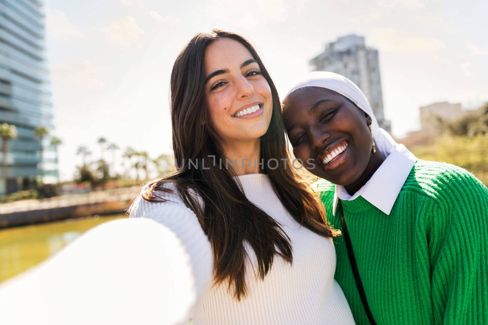 selfie photo of two young women friends smiling happy and carefree in a city park, concept of diversity and modern lifestyle