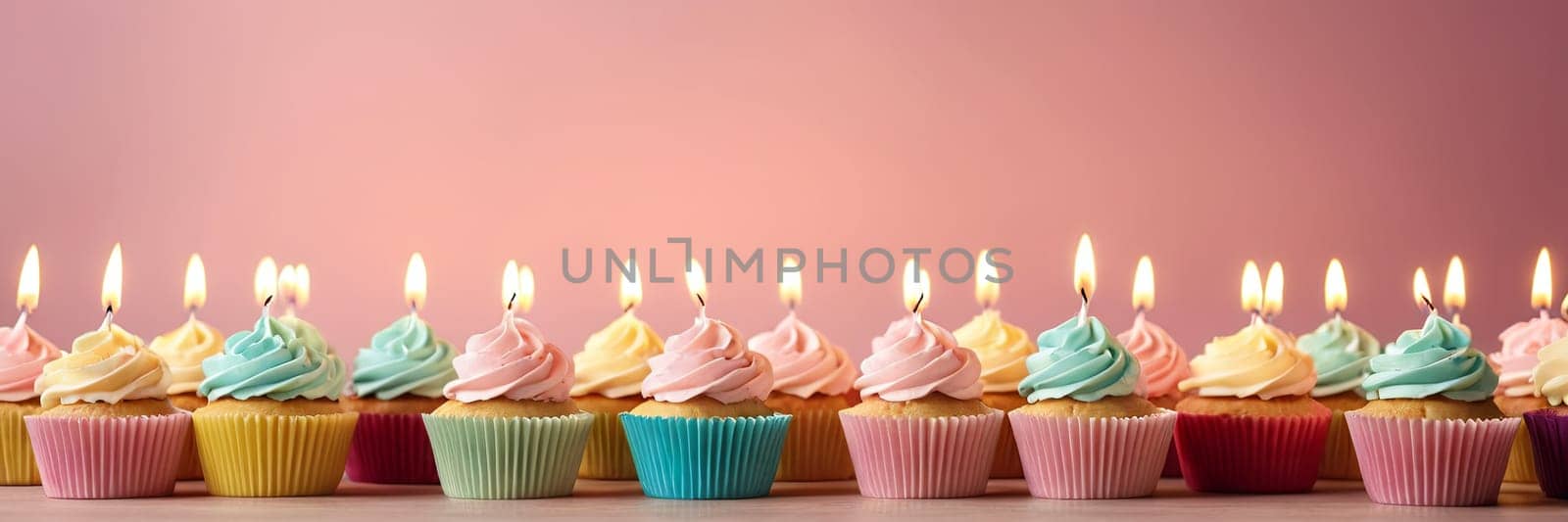 Colorful cupcakes with lit candles are displayed against a pink background, indicating an indoor celebration event marking of joy and celebrating. with free space.