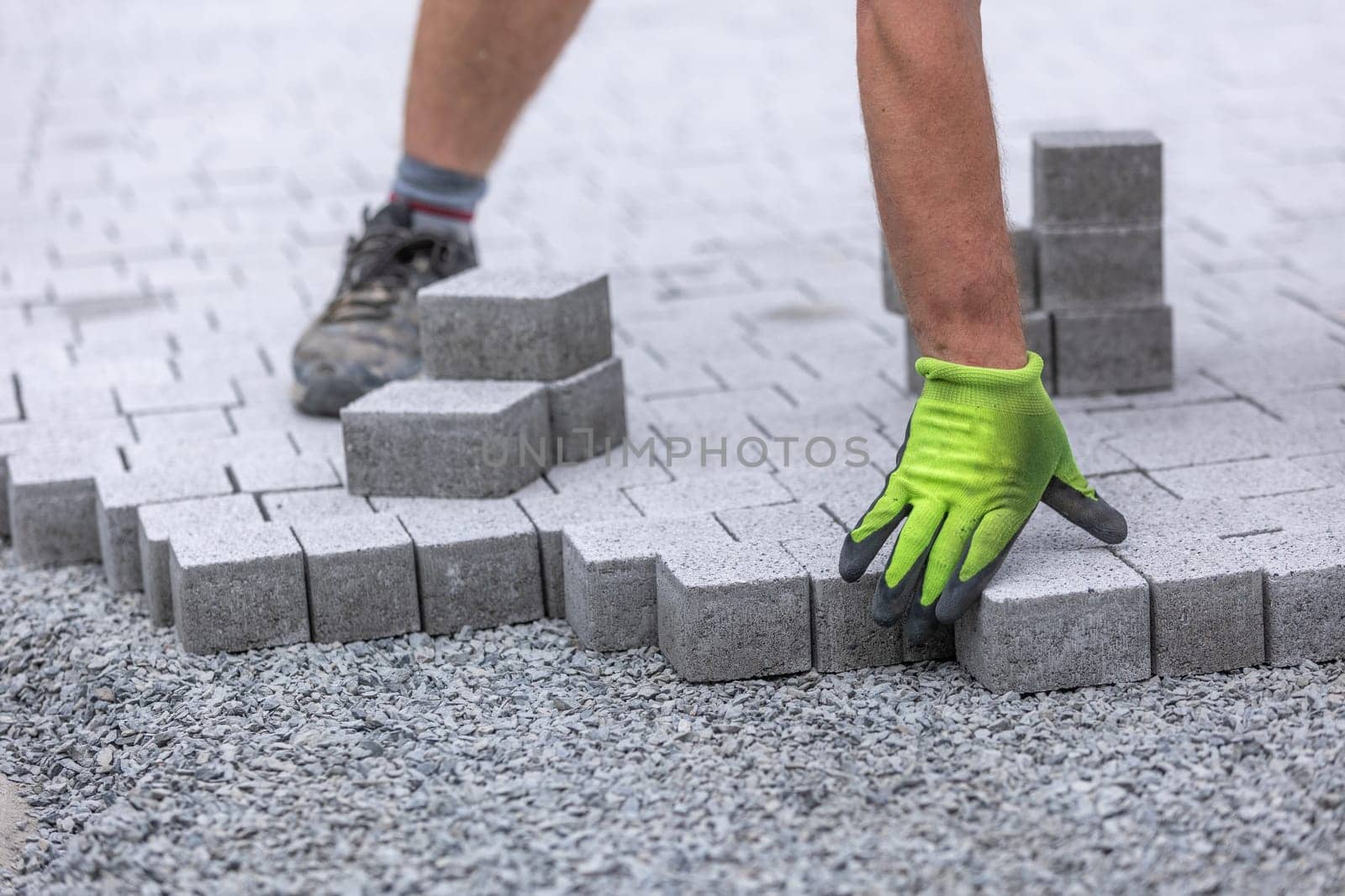 Process of building sidewalk, a aworker laying interlocking walking path, industrial concept