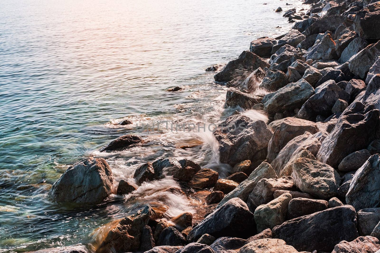 Background of clear waters against a rocky beach.