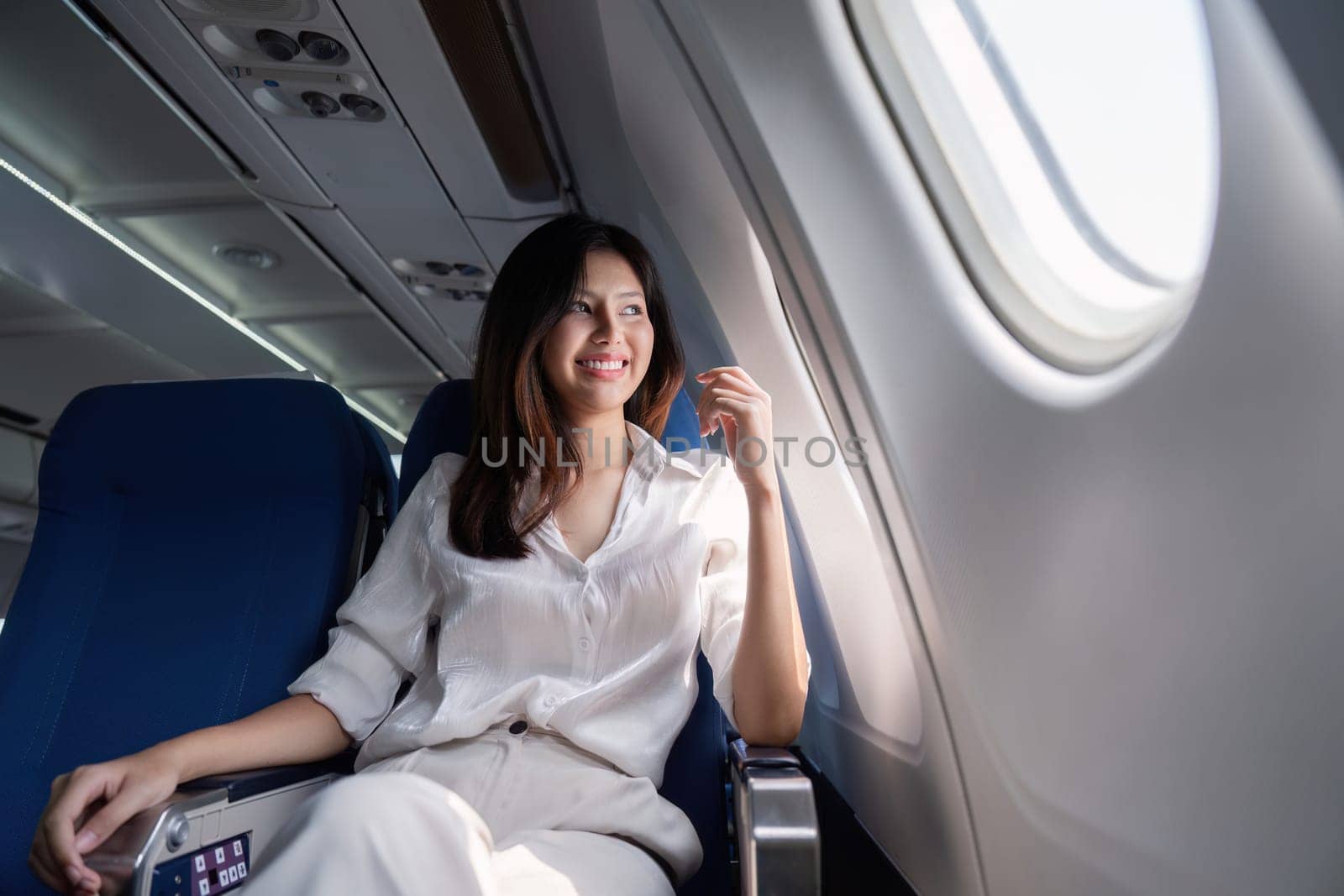 Businesswoman traveling on airplane seat. Concept of business travel and work by nateemee