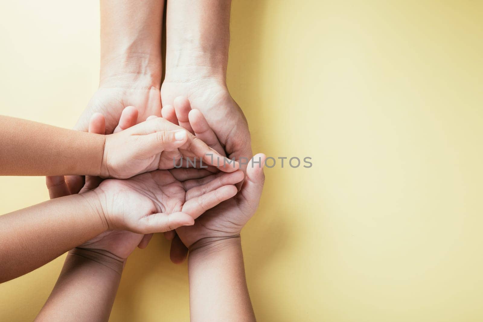 Emphasizing Family and Parents Day, Top view studio shot displays family hands stacked against an isolated background. Parents and children hold an empty space signifying support. by Sorapop