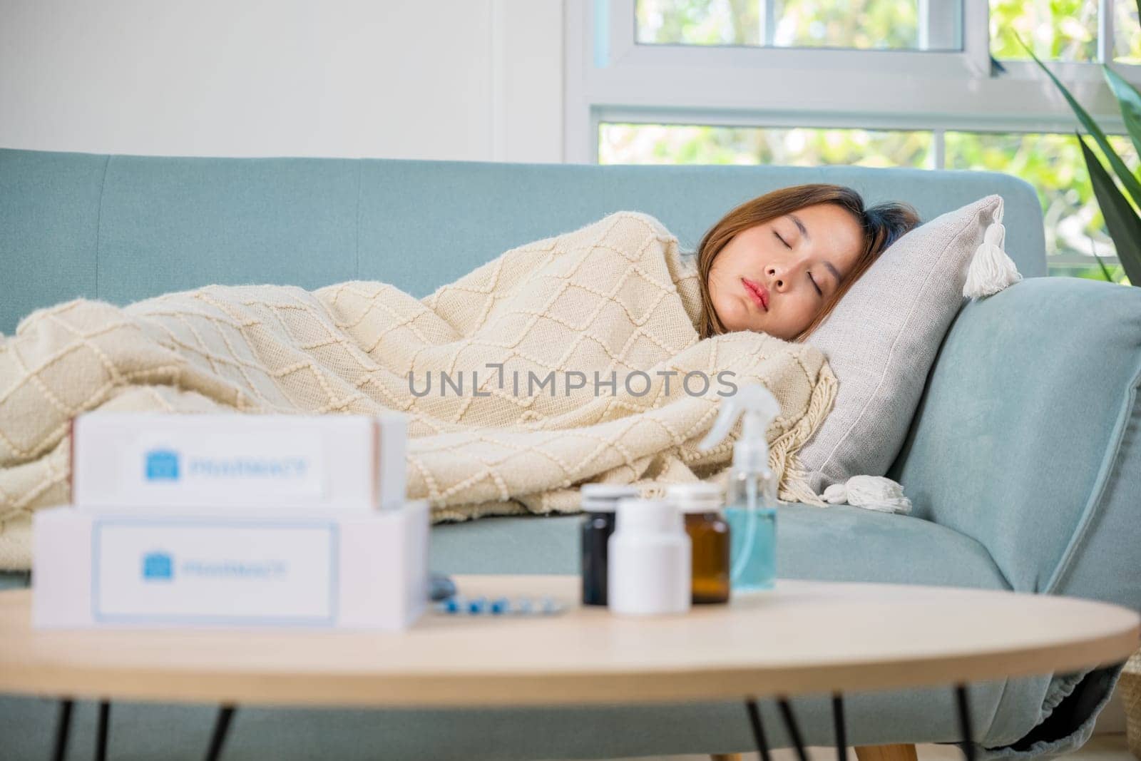 Asian young woman cold sick she sleeping and resting on sofa after take pills at home, beautiful female health problem use pharmacy kit box delivery service from hospital, delivery pharmacy concept