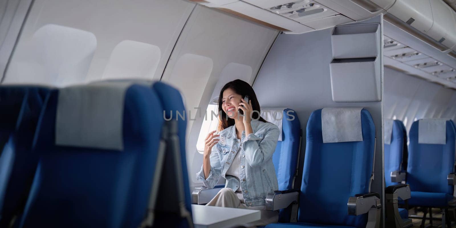 Businesswoman traveling on airplane and making a phone call by nateemee