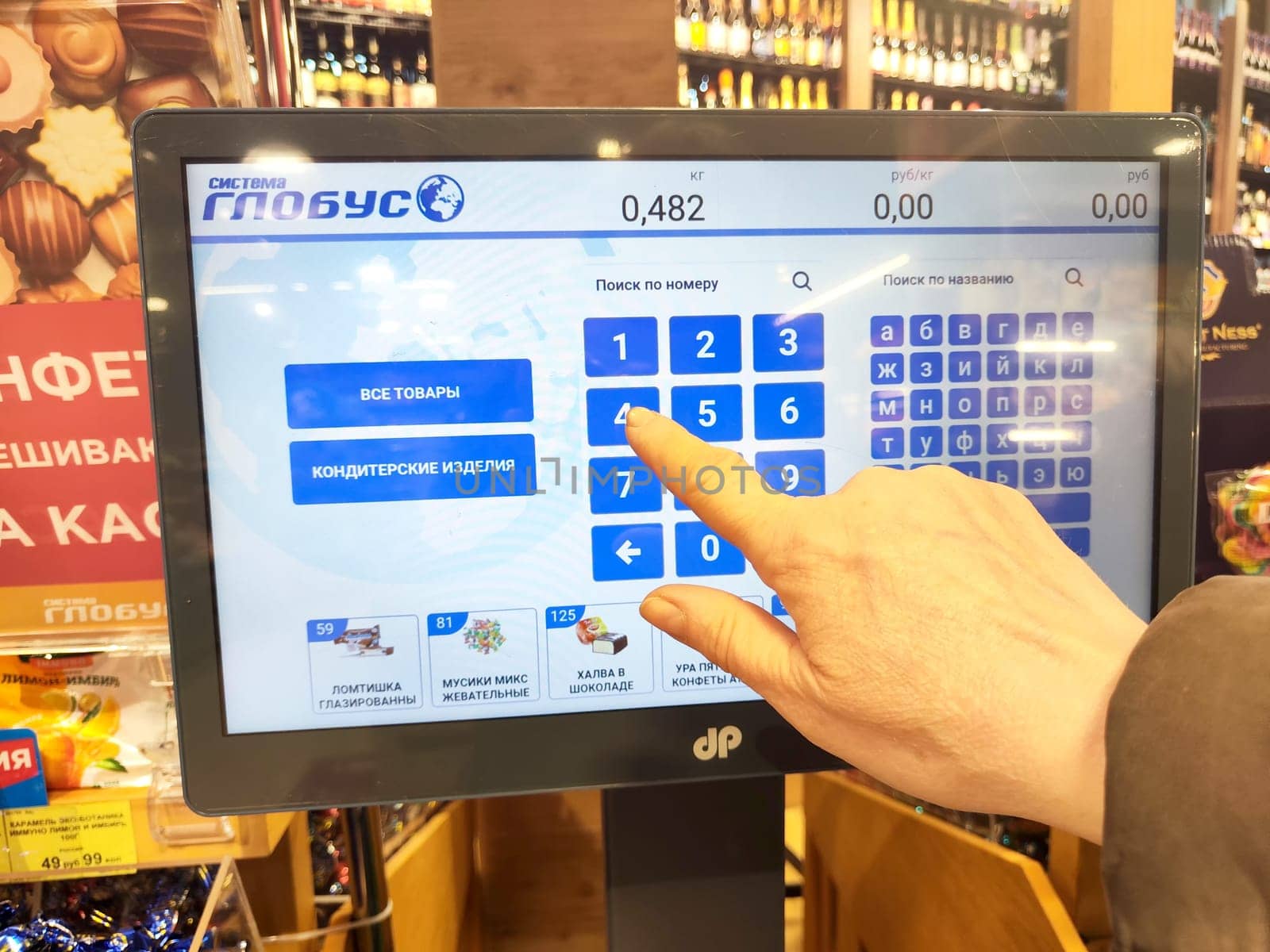 Kirov, Russia - April 17, 2024: Customer Weighing Produce on Digital Scales at Grocery Store. A person is using a touchscreen to weigh items at store