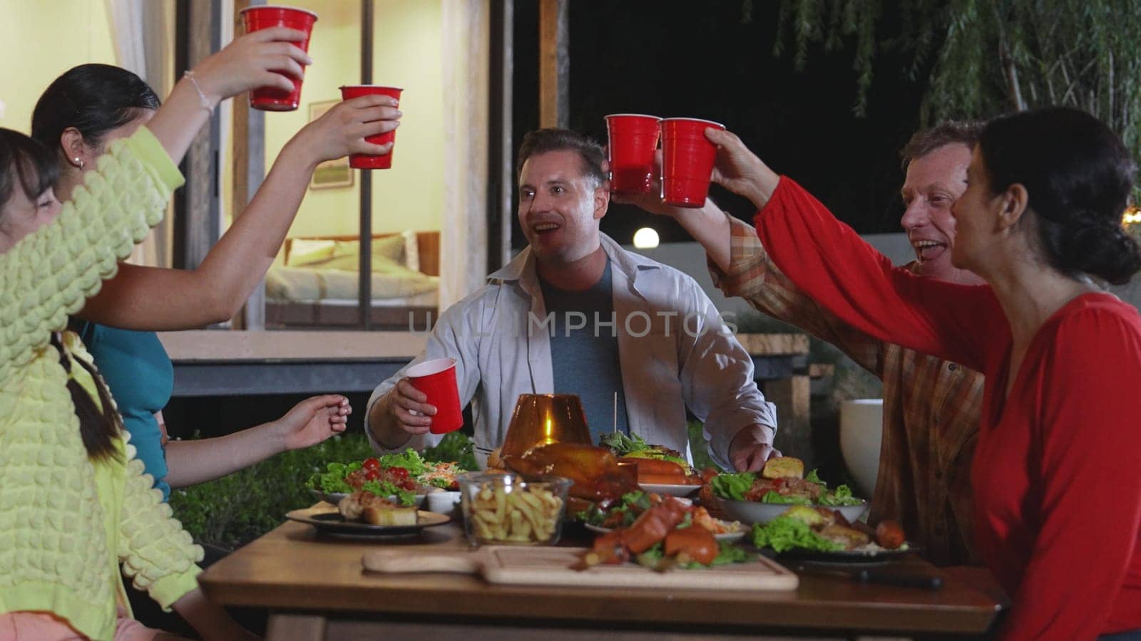 Family together celebrate holiday in garden. Grandparents, parents and daughter use beverage glass cheers for celebration. Outdoor camping activity relax with meal strengthen family bond. Divergence.