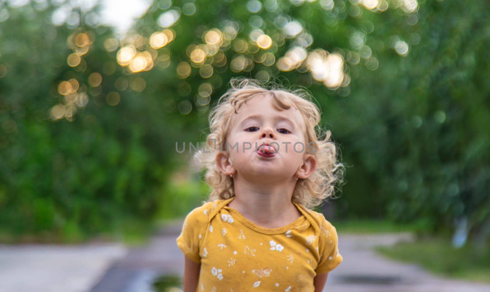 Child sticks out tongue on street portrait. Selective focus. Kid.