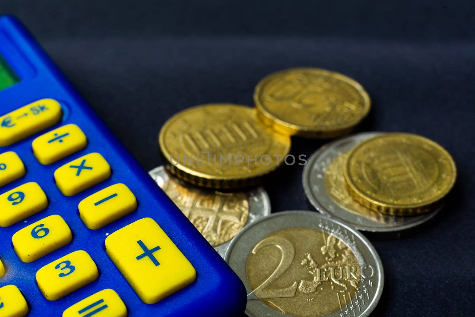 Money concept. Blue calculator with coins euro, close up, dark background by Zelenin