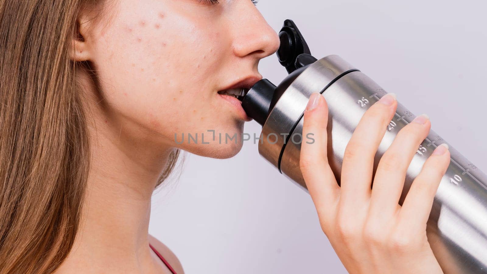 Sporty muscular woman drinking water, isolated against white background by Zelenin